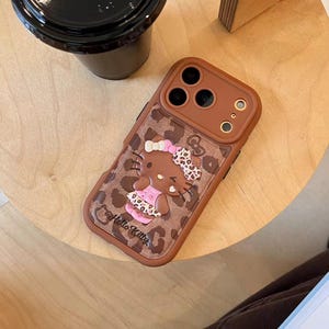 Läderfodral i rosa brunt leopardmönster med Hello Kitty-motiv och snodd för iPhone 17 Pro, 16 Pro Max och 15-serien. bild 5