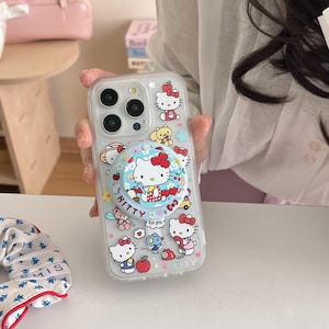May include: Clear phone case with a pop-up grip featuring Hello Kitty characters. The case has a variety of Hello Kitty illustrations, including the character with a red bow. The pop-up grip has the text "Kitty" and "for you".