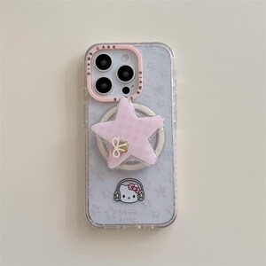 K&ouml;nnte beinhalten: Transparente Handyh&uuml;lle mit einem rosa sternf&ouml;rmigen Handyhalter und einem Hello Kitty-Motiv. Die H&uuml;lle hat einen rosa Kamerarand und einen wei&szlig;en Ringhalter. Der Hintergrund hat ein Muster aus kleinen Sternen.