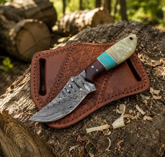 Turquoise-inlaid rosewood handle on a Damascus blade with a cowhide sheath — the turquoise detail is genuinely eye-catching and unusual in this category.
