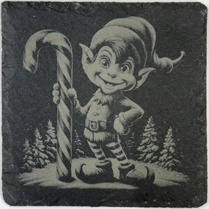 May include: A square, dark gray slate coaster featuring a whimsical illustration of a smiling elf holding a candy cane. The elf is wearing a hat, striped pants, and a belt. The background includes stylized pine trees and a starry night sky.