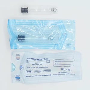 Puede incluir: Un surtido de suministros de esterilización médica, que incluye un tubo de vidrio transparente con componentes negros y plateados, y una bolsa termosellable azul y blanca. La bolsa está etiquetada "HTC STERILIZATION POUCH", dimensiones 57mm x 130mm.