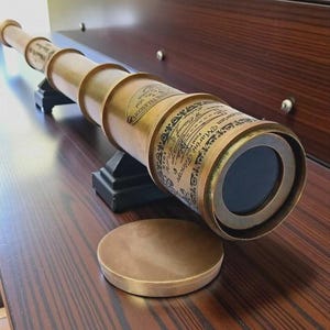 Peut inclure: Une longue-vue marine en laiton avec un corps cylindrique et un capuchon d'objectif circulaire. Le télescope présente une inscription gravée Victorian Marine Telescope, W. Ottway & Co, London, 1915, et repose sur un support noir.