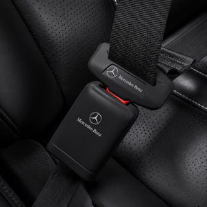 Può includere: Primo piano di una fibbia e di un ricevitore per cintura di sicurezza Mercedes-Benz neri. Il logo Mercedes-Benz è visibile su entrambi i pezzi. La cintura di sicurezza è nera e l'interno sembra essere in pelle nera.