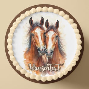 Könnte beinhalten: Ein runder Kuchen mit braunem Rand und weißem Zuckerguss. Der Kuchen zeigt eine Aquarellillustration von zwei braunen Pferden mit weißen Abzeichen. Der Text "Wunschtext" ist in einer Schreibschrift auf dem Kuchen geschrieben.