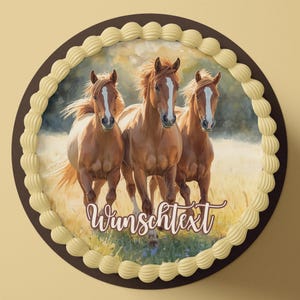 Puede incluir: Una tarta redonda con borde marrón y borde crema. El centro de la tarta presenta una pintura de tres caballos marrones con marcas blancas, corriendo por un campo. El texto "Wunschtext" está escrito en cursiva.