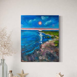 以下が含まれることがあります： 青い空と海が描かれた油絵の風景画。赤い太陽、白い波、緑の陸地が特徴です。アーティストのサイン「Kilanova」が見えます。絵は額装され、白い壁に掛けられています。