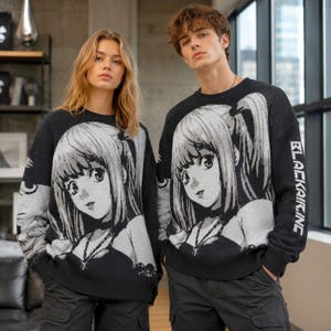 May include: A black long-sleeve crewneck jumper featuring a large, high-contrast white and grey graphic of an anime-style character with long hair. The text "BLACKAIRINC" is printed in white capital letters vertically along the left sleeve.