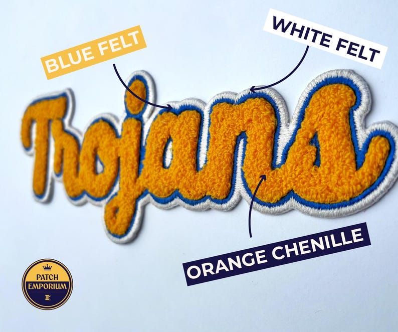 May include: An orange chenille patch with the word "Trojans" in a script font. The patch has a blue felt outline and white felt border. The patch is from Patch Emporium.