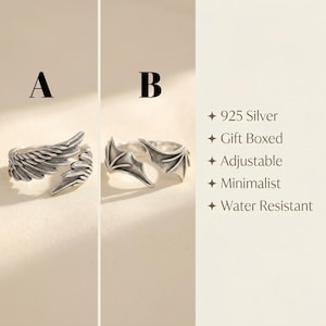Pode incluir: Dois an&eacute;is de prata rotulados A e B. O anel A apresenta um design de asa de anjo, enquanto o anel B exibe um design de asa de morcego. O texto &agrave; direita lista as caracter&iacute;sticas: 925 Silver, Gift Boxed, Adjustable, Minimalist, Water Resistant.