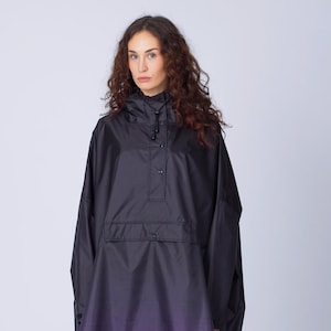 May include: Black hooded poncho with a purple ombre design. The poncho features a buttoned closure and a subtle cross pattern at the hem. The garment is worn with dark leggings and black ankle boots, creating a modern, stylish look.