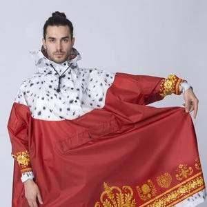 May include: A red and white hooded poncho with a royal design. The poncho features a white top with black spots, a red lower section with gold crown and emblem details, and white faux fur trim. The sleeves have gold accents.