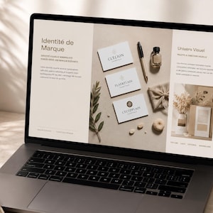 Puede incluir: Un ordenador port&aacute;til muestra un dise&ntilde;o web con las palabras "Identit&eacute; de Marque" y "Univers Visuel". La pantalla muestra tarjetas de visita, un bol&iacute;grafo, una botella peque&ntilde;a y un regalo envuelto. Tambi&eacute;n se ven un cuaderno, un bol&iacute;grafo y una taza de caf&eacute;.