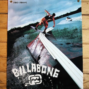 May include: Poster depicting a watersports scene with a person wakeboarding. The poster has the text "CHAD SHARPE" at the top and "BILLABONG" in large white letters at the bottom. The background shows water and a boat.