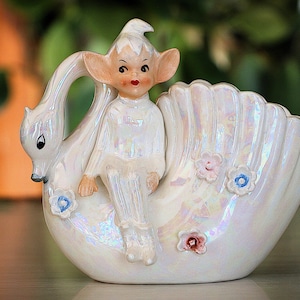 May include: A white ceramic mug with a black handle and the text "But First, Coffee" in a black, handwritten-style font. The mug is on a white surface.