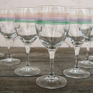 Peut inclure: Ensemble de six verres à vin transparents ornés de rayures colorées. Chaque verre présente des rayures horizontales vertes, violettes et pêche. Les verres ont une tige fine et un pied rond, parfaits pour servir du vin.
