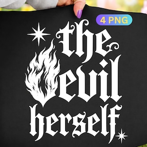 Puede incluir: Bolso tote negro con el texto "the evil herself" en fuente gótica, acompañado de un gráfico de llama y estrellas. El bolso es sostenido por una persona.