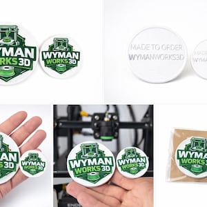 Puede incluir: Dos parches redondos blancos con el texto "WYMAN WORKS 3D" en verde y blanco. Los parches presentan un gráfico de impresora 3D y una bobina de filamento verde. El texto "MADE TO ORDER WYMANWORKS3D" está en la parte posterior.
