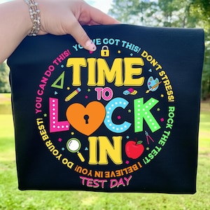 Puede incluir: Camiseta negra con la frase "TIME TO LOCK IN" en amarillo, naranja y azul, rodeada de gráficos coloridos y las frases "You can do this!" y "Test Day".