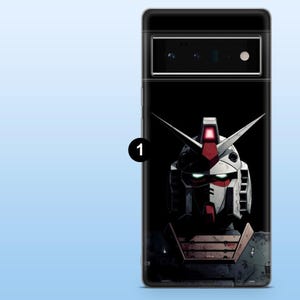 May include: A black phone case featuring a detailed illustration of a robot's head. The robot has a white and red color scheme with sharp, angular features and glowing green eyes. The case is designed for a phone.