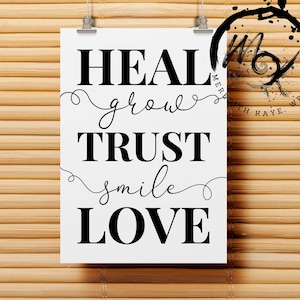 May include: A white poster with the words "HEAL, grow, TRUST, smile, LOVE" in black, hanging against a bamboo background. The words are in a mix of bold and cursive fonts. The poster is held by two silver clips.