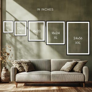 a living room with a sofa and a potted plant. The sofa has a striped pattern, and there are four framed pictures of different sizes displayed on the wall above it.