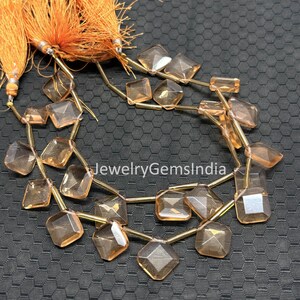 May include: Strands of faceted, amber-colored gemstone beads with gold-toned connecting wires. The beads are various geometric shapes. Orange tassels are visible at the top. The text "jewelryGemsIndia" is visible in the image.