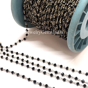 Könnte beinhalten: Eine Spule mit schwarzer Perlenkette mit silberfarbenem Draht. Die Kette ist eng auf eine hellblaue Spule gewickelt. Der Text "jewelryGemsIndia" ist auf der Spule zu sehen.