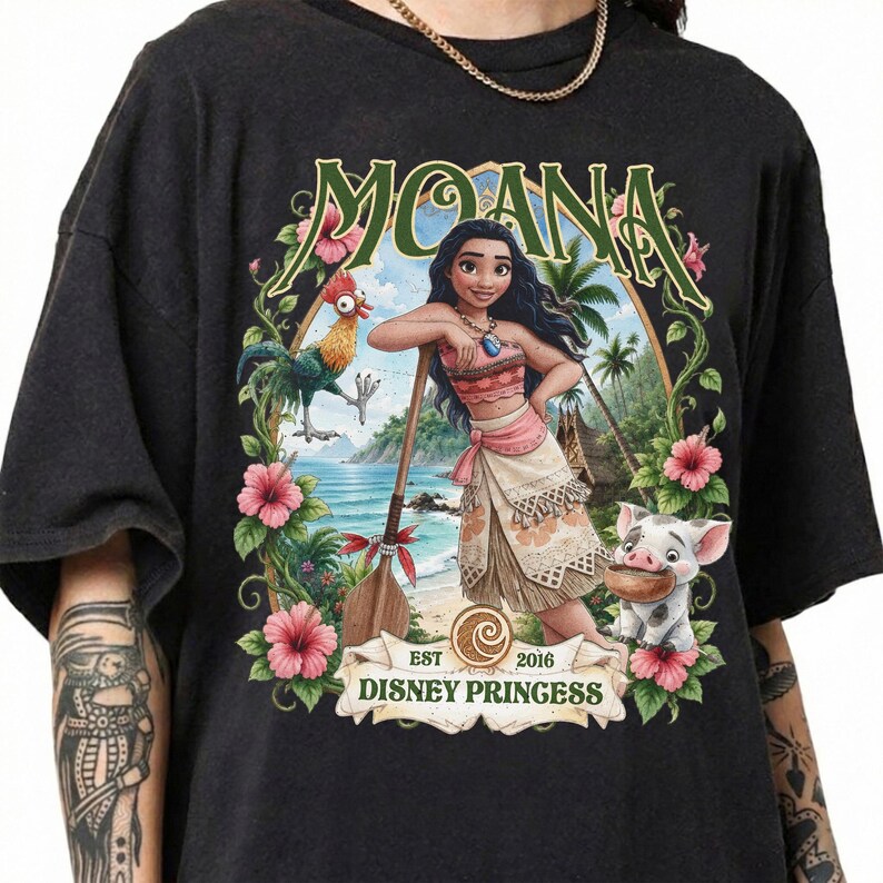 May include: A black t-shirt featuring a graphic of Moana, Hei Hei the rooster, and Pua the pig. The design includes tropical flowers, a wooden oar, and the text MOANA and EST 2016 DISNEY PRINGESS in a decorative frame against a beach background.
