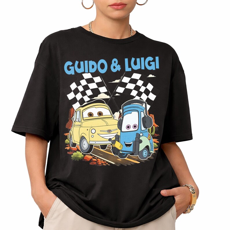 May include: Black t-shirt featuring a cartoon graphic of two cars, a yellow one and a blue one, with the text "GUIDO & LUIGI" above them. The cars are on a road with checkered flags in the background.