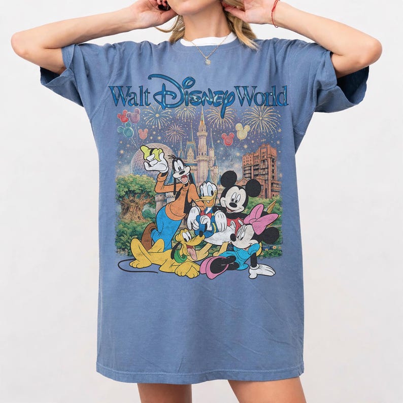 Pu&ograve; includere: T-shirt blu con la scritta "Walt Disney World" e una grafica dei personaggi Disney: Topolino e Minnie, Pippo e Pluto. La grafica include anche un castello, fuochi d'artificio e palloncini.