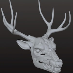 Puede incluir: Escultura gris claro de una cabeza de ciervo con grandes cuernos. La cara tiene una apariencia esquelética con dientes visibles y múltiples cuencas oculares, creando un diseño único y fantástico.