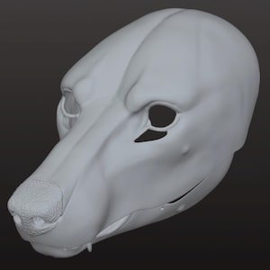 Può includere: Una maschera canina grigio chiaro stampata in 3D, con dettagliati tratti del viso. La maschera ha orbite oculari aperte, un naso strutturato e una mascella definita. Il design suggerisce una rappresentazione realistica, ma stilizzata, di una testa di cane.