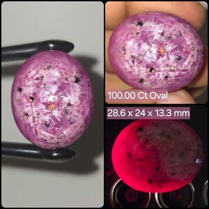 Op de afbeelding: Een ovaalvormige roze edelsteen met zwarte insluitingen en een gepolijst oppervlak. De steen is gelabeld als 100.00 Ct Oval en meet 28,6 x 24 x 13,3 mm. Eén aanzicht toont de steen onder fel licht, wat een levendige, gloeiende rode tint onthult.