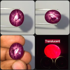 May include: A round, cabochon-cut ruby gemstone with a deep magenta-red color and a visible star-like optical effect. The stone displays internal inclusions and a translucent quality when backlit, appearing as a bright, glowing red orb in the dark.