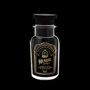 Puede incluir: Una botella de colonia de vidrio transparente con tapa negra y etiqueta negra y dorada. La etiqueta dice "HEARSE Cologne" y enumera las notas de la fragancia. La botella contiene 30 ml de colonia.