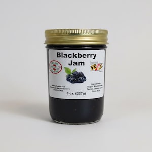 以下が含まれることがあります： 金色の蓋が付いたブラックベリージャムの瓶。ラベルには「Blackberry Jam」と書かれており、ブラックベリーと葉のグラフィックがあります。瓶には227gのジャムが入っています。材料には、砂糖、ブラックベリー、ペクチン、レモンジュース、クエン酸が含まれています。