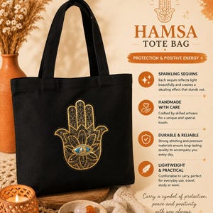 May include: A black tote bag featuring a gold embroidered Hamsa hand design with a central blue eye motif. The text on the bag's promotional graphic includes HAMSA TOTE BAG, PROTECTION & POSITIVE ENERGY, SPARKLING SEQUINS, HANDMADE WITH CARE, DURABLE & RELIABLE, and LIGHTWEIGHT & PRACTICAL.