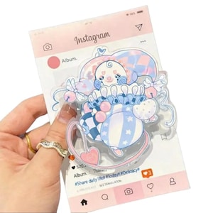 May include: A clear acrylic charm featuring a whimsical clown design in pastel blue, pink, and white. The charm is set against a pink Instagram-themed background with the text "Album" and "#Share daily lifelt #Today #Delicacy#".