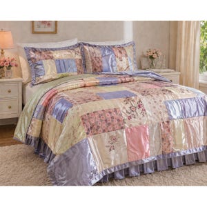 May include: A patchwork quilt and two pillow shams in pastel colors, including pink, lavender, and cream. The quilt features a satin border and a ruffled skirt. Floral patterns and solid squares make up the design. The bedding set is on a bed with a white headboard.