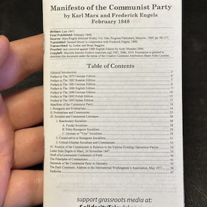 May include: A pamphlet titled "Manifesto of the Communist Party" by Karl Marx and Frederick Engels, published in February 1848. The cover features text and a table of contents, with the website SolidarityTelevision.org at the bottom.