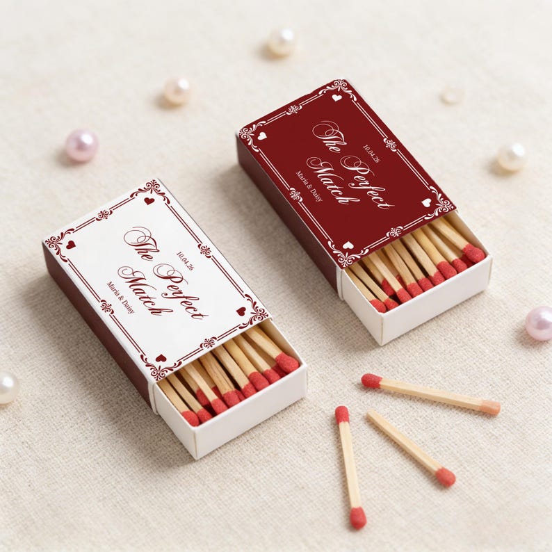 May include: Two open matchboxes with the text "The Perfect Match" and the date 10.04.20, along with the names Maria & Daisy. The matchboxes are burgundy with white and burgundy decorative borders. Several matches are scattered around.
