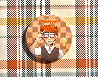 Può includere: Una spilla rotonda con l'illustrazione di una persona con capelli arancioni e occhiali, che indossa una camicia bianca e un gilet scuro. Lo sfondo presenta un motivo a scacchi arancione e beige con la scritta Sumner stampata in alto.