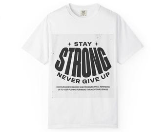 May include: White t-shirt with the words "STAY STRONG NEVER GIVE UP" in bold black letters. The text is centered on the shirt, with additional text below that reads "ENCOURAGES RESILIENCE AND PERSEVERANCE, REMINDING US TO KEEP PUSHING FORWARD THROUGH CHALLENGES."