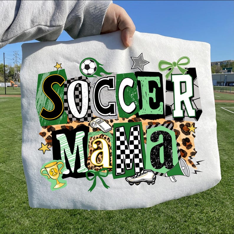 May include: White soccer-themed graphic design on a white background. The design includes the words "SOCCER MAMA" in various fonts and colours, along with soccer balls, stars, a trophy, and a whistle.