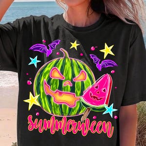 May include: A black t-shirt featuring a graphic of a green watermelon carved like a jack-o'-lantern, a pink watermelon slice carved like a jack-o'-lantern, purple bats, and yellow and blue stars, with the word "summerween" in pink cursive text.