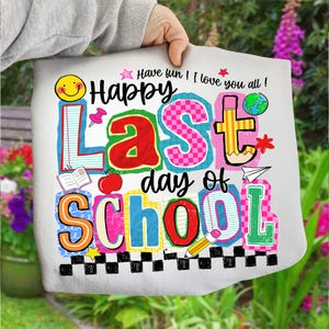 Pode incluir: Uma sacola branca com a frase "Happy Last Day of School" em letras coloridas e divertidas. O design inclui um rosto sorridente, um l&aacute;pis, uma ma&ccedil;&atilde; e um globo, celebrando o fim do ano letivo.