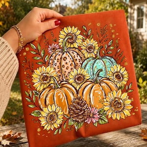 May include: A burnt orange fabric square featuring a graphic print of three pumpkins, one with a leopard print pattern and one in teal, surrounded by yellow sunflowers, green leaves, a pinecone, and small pink flowers with gold glitter accents.