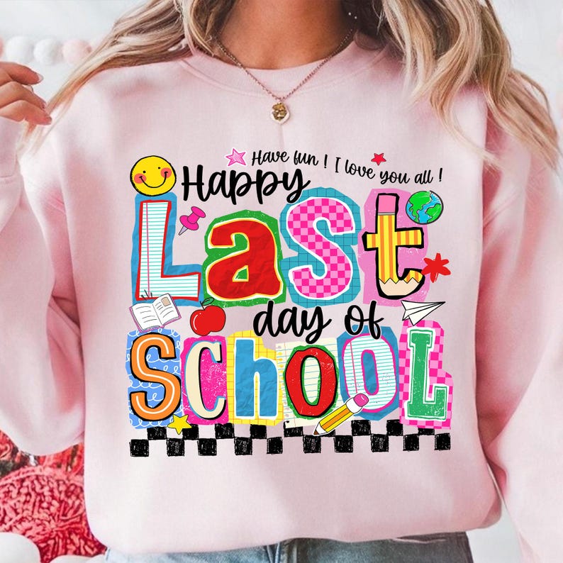 Pode incluir: Um moletom rosa claro com um gr&aacute;fico colorido que diz "Happy Last Day of School". O design inclui uma ma&ccedil;&atilde;, um l&aacute;pis, um globo e outros elementos escolares. O texto "Have fun! I love you all!" tamb&eacute;m est&aacute; inclu&iacute;do.