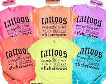 May include: A collection of six short-sleeve t-shirts in neon pink, neon cantaloupe, neon violet, neon red orange, neon lemon, and lagoon blue. Each shirt features black text reading: tattoos because life is hard AND I DESERVE stickers.